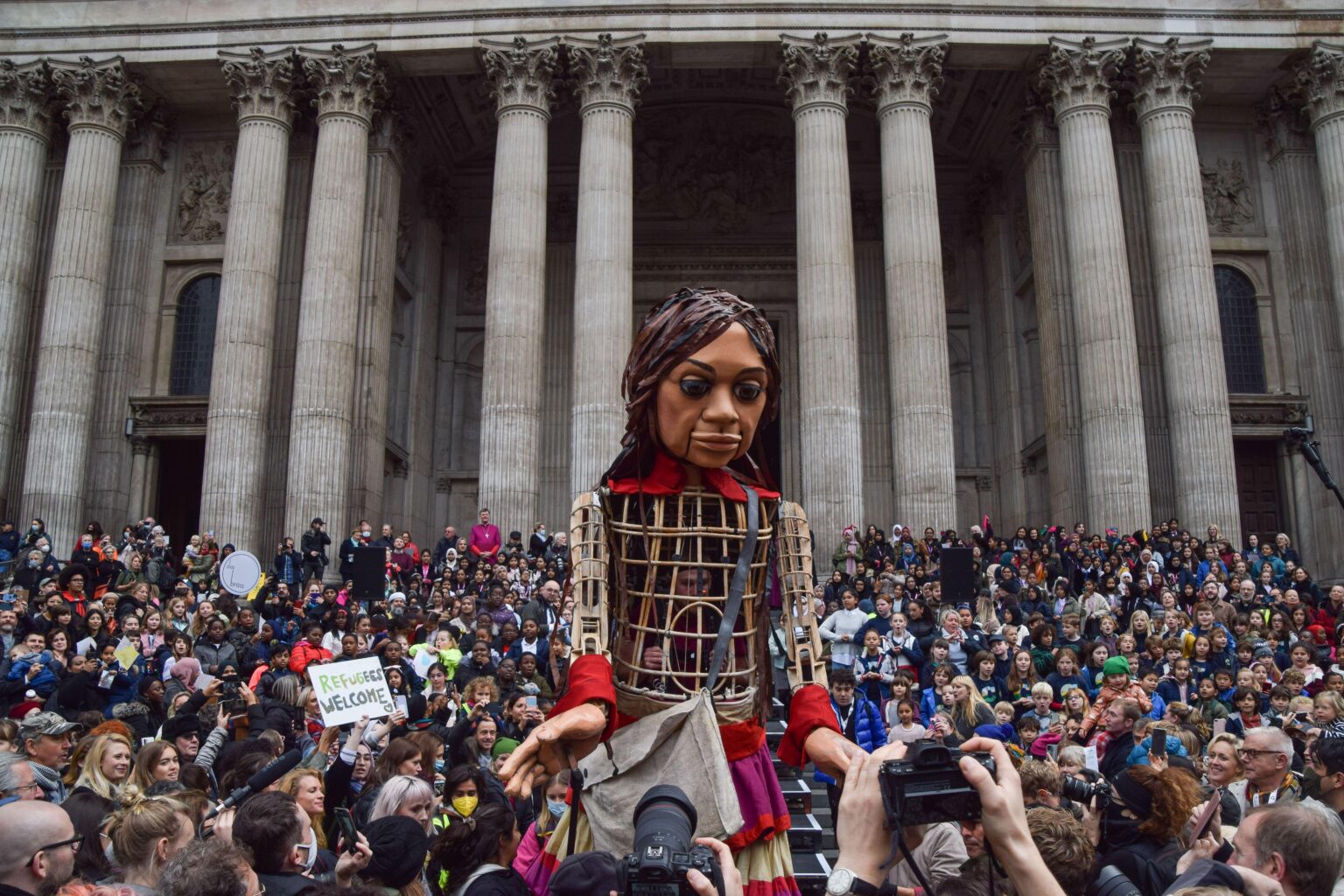 London, UK. 23rd October 2021. Crowds gather outside St Paul’s Cathedral to welcome Little Amal. A 3.5 metre tall puppet representing a Syrian refugee child, Little Amal’s journey began close to the Turkish Syrian border, travelling 8,000 km across Europe